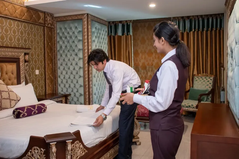 Hotel staff coordinating room cleaning and preparing a guest bed for a comfortable stay