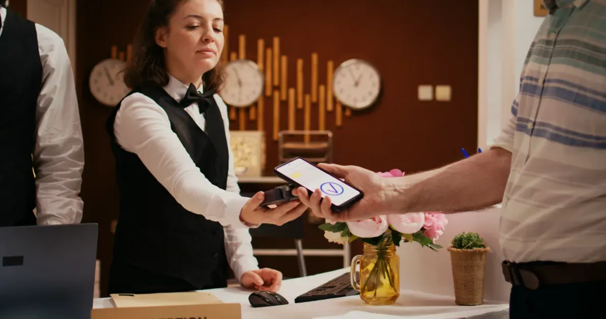 Hotel receptionist using a digital device to process a guest payment during check-in